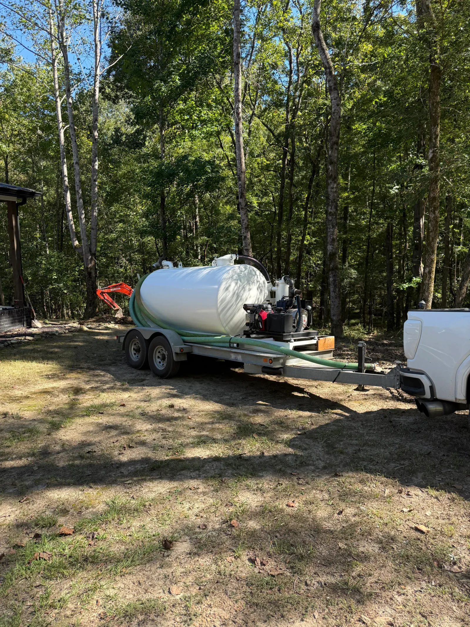 Dual-axle septic vacuum trailer with stainless steel tank and pump system on residential property